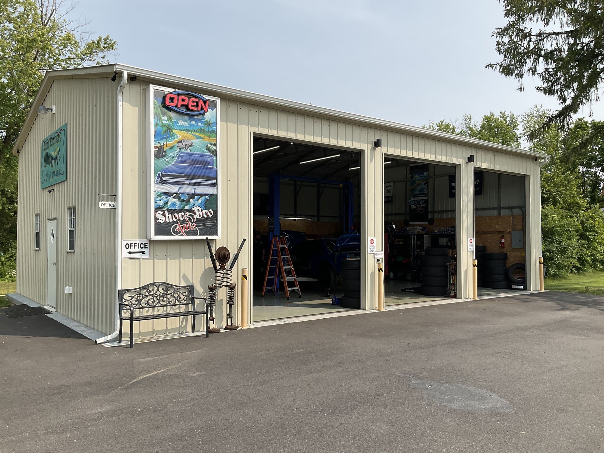 Exterior of the Shore Bro Auto shop with three open service bays and an OPEN sign